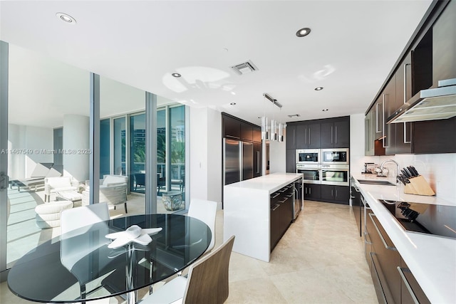 kitchen with pendant lighting, sink, a wall of windows, built in appliances, and dark brown cabinetry