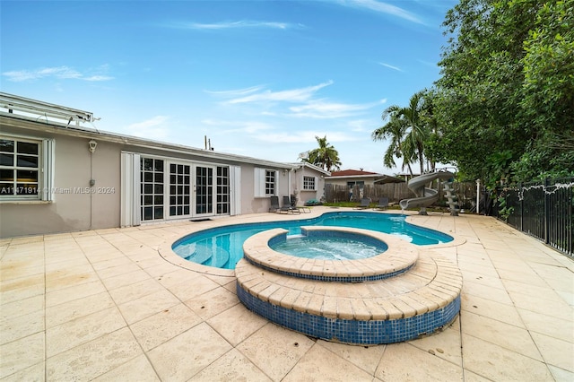 view of pool with a water slide, an in ground hot tub, and a patio area