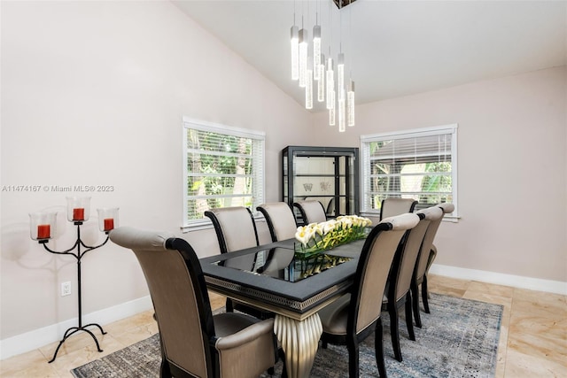 dining area featuring light tile flooring, high vaulted ceiling, and an inviting chandelier