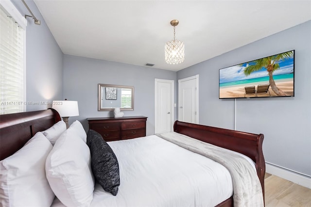 bedroom featuring light hardwood / wood-style floors and a notable chandelier