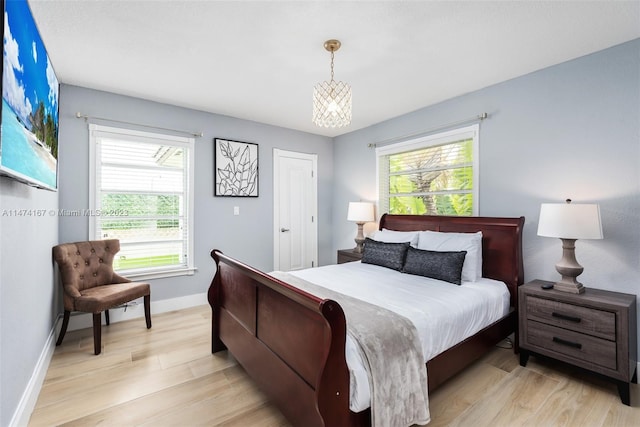 bedroom featuring an inviting chandelier and light hardwood / wood-style flooring