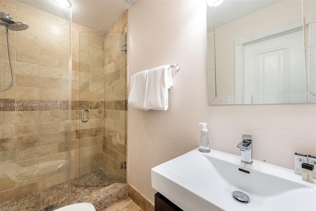 bathroom with a shower with shower door and sink
