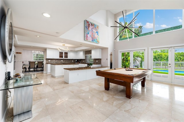 recreation room featuring a high ceiling, pool table, french doors, and light tile floors