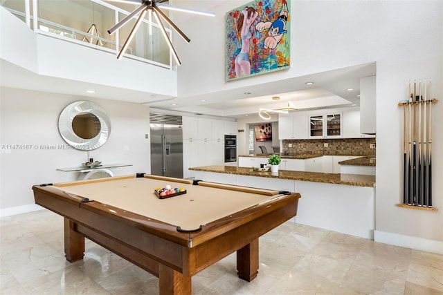 recreation room with light tile floors, billiards, a tray ceiling, and a towering ceiling