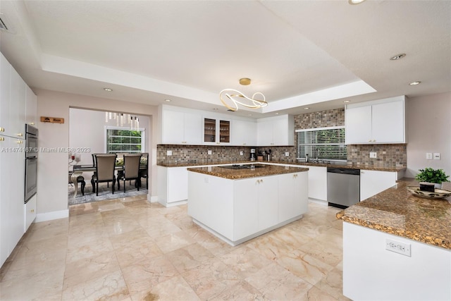 kitchen featuring a kitchen island, stainless steel appliances, white cabinetry, and a tray ceiling
