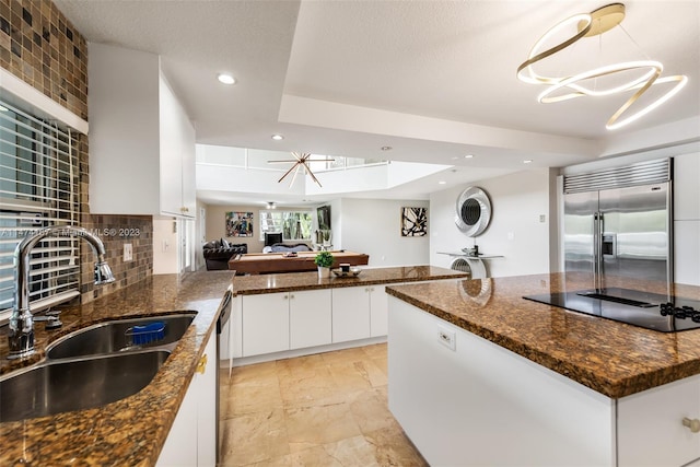 kitchen with tasteful backsplash, appliances with stainless steel finishes, a tray ceiling, and dark stone counters