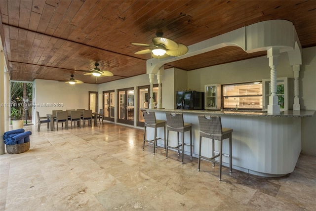 kitchen featuring light tile floors, wooden ceiling, ceiling fan, and black fridge