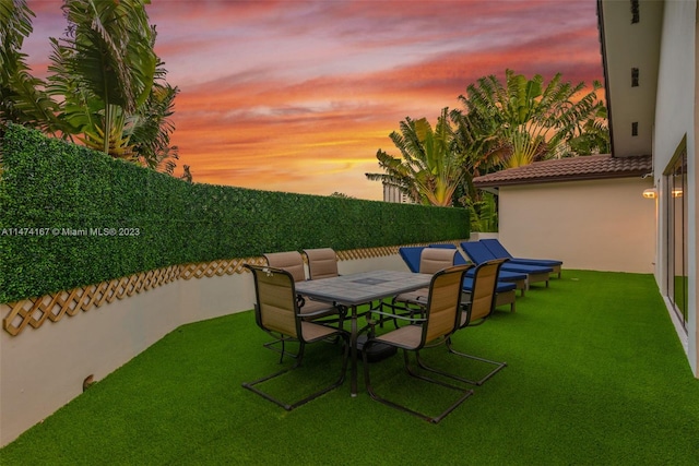 patio terrace at dusk featuring a lawn and an outdoor living space