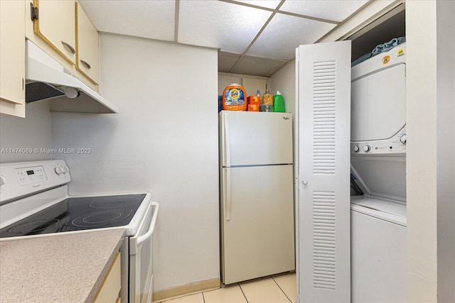 kitchen with light tile floors, white appliances, stacked washer and dryer, and a paneled ceiling