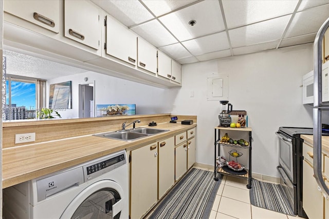 kitchen featuring white cabinetry, washer / dryer, sink, light tile floors, and a drop ceiling