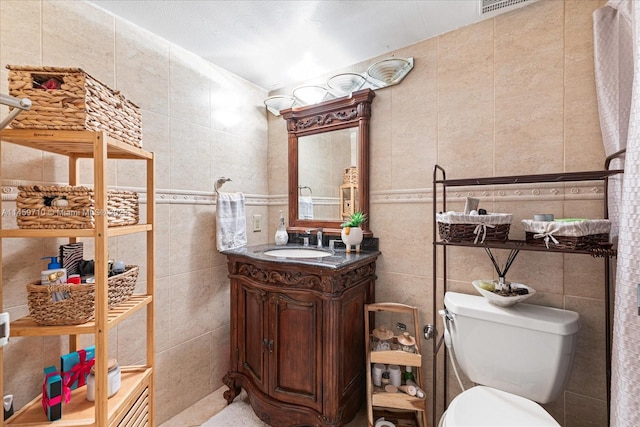 bathroom featuring vanity, toilet, and tile walls