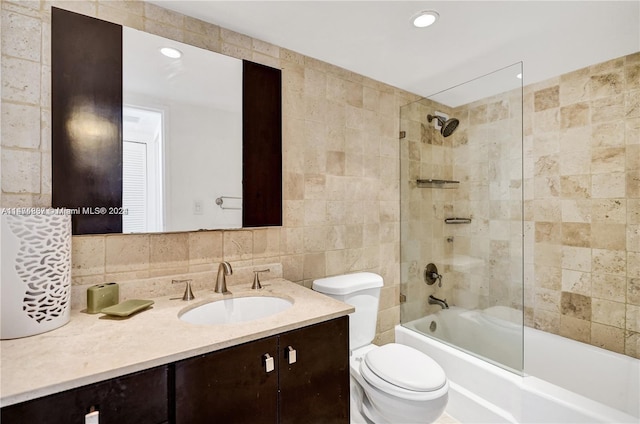 full bathroom with vanity, tile walls, tiled shower / bath, toilet, and tasteful backsplash