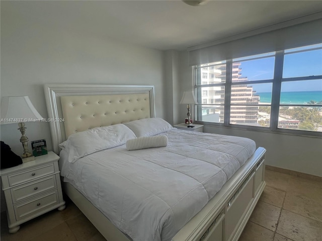 bedroom featuring a water view, light tile floors, and multiple windows