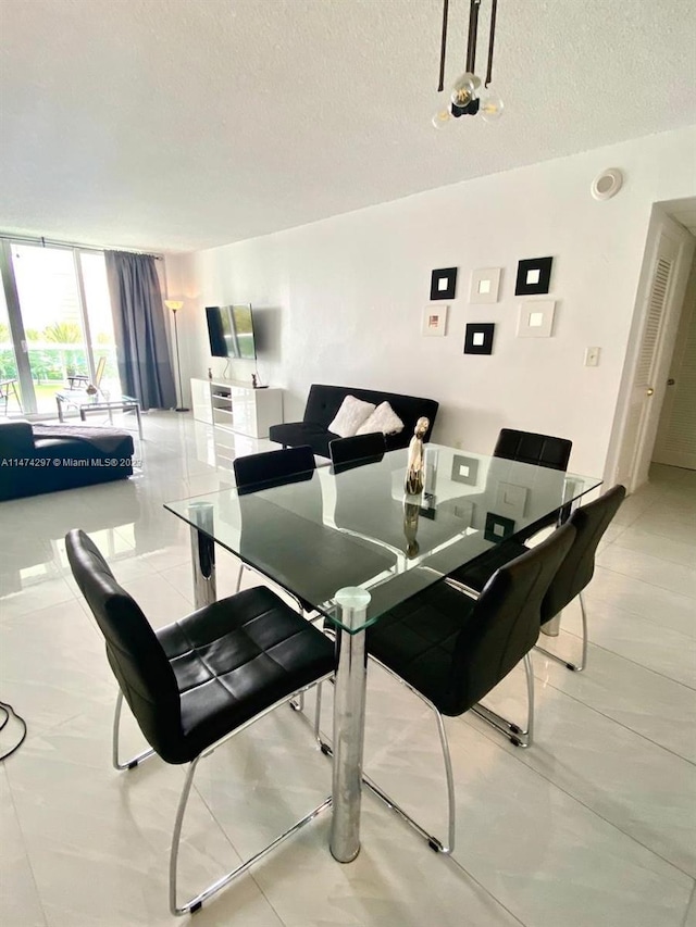 dining room featuring light tile floors, a textured ceiling, and a wall of windows