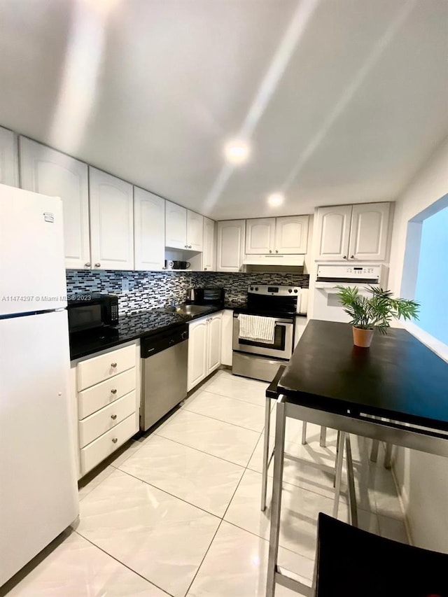 kitchen with stainless steel appliances, light tile floors, tasteful backsplash, white cabinets, and sink