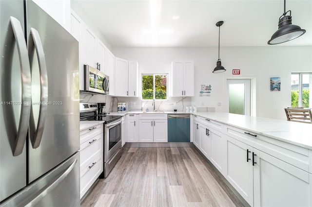 kitchen featuring light wood-type flooring, tasteful backsplash, appliances with stainless steel finishes, and a wealth of natural light