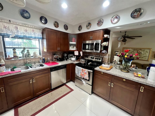 kitchen with ceiling fan, sink, appliances with stainless steel finishes, backsplash, and light tile flooring