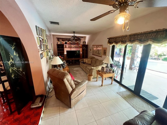 living room featuring light tile floors, a textured ceiling, and ceiling fan