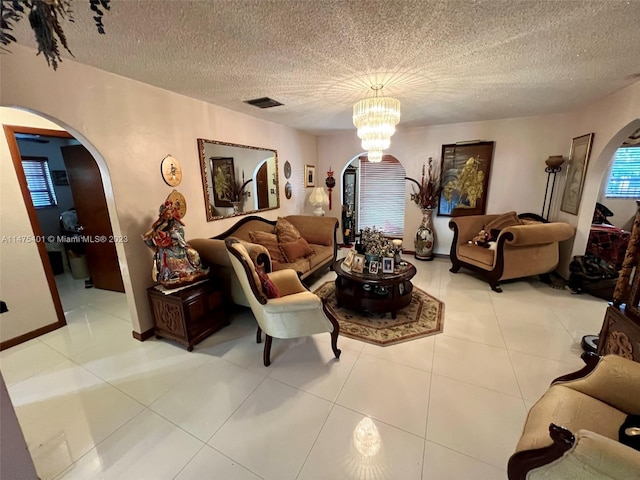 tiled living room featuring a textured ceiling and a chandelier