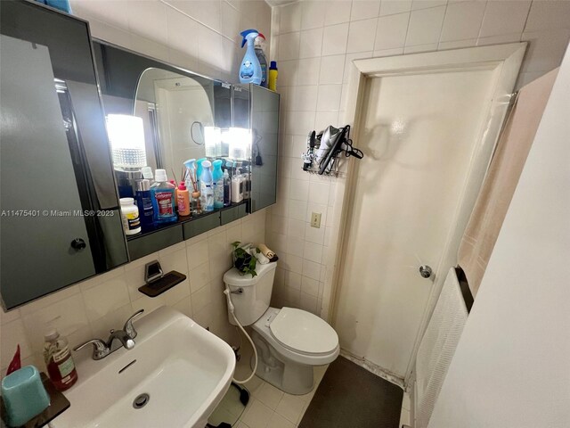 bathroom featuring tile walls, toilet, sink, tile floors, and tasteful backsplash