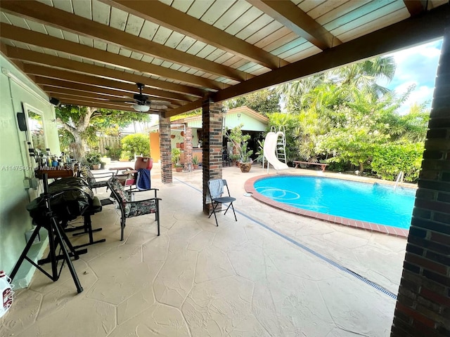 view of pool featuring a water slide, ceiling fan, and a patio area