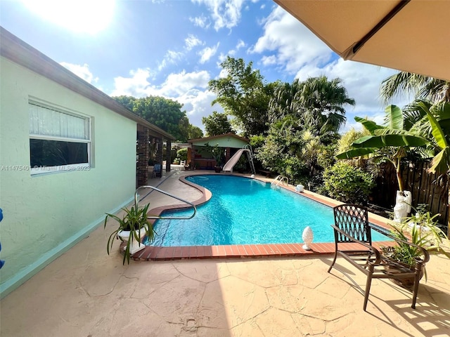 view of swimming pool featuring a water slide and a patio