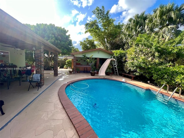 view of swimming pool with a water slide and a patio area