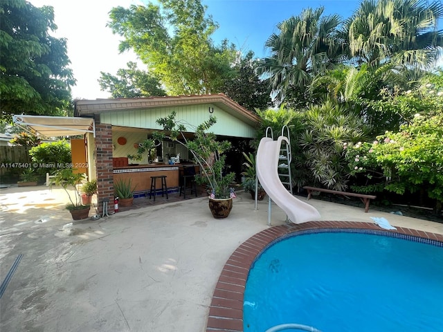 view of swimming pool with a water slide and a patio