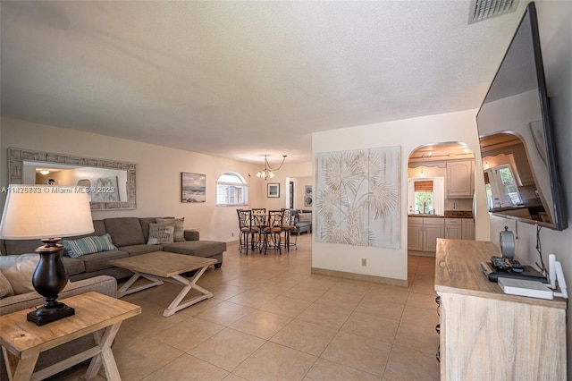 living room featuring a textured ceiling, a chandelier, and light tile flooring