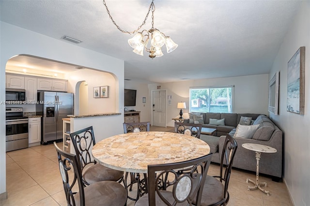 tiled dining space featuring a notable chandelier and a textured ceiling