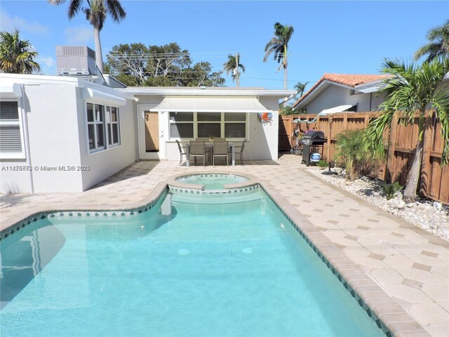 view of swimming pool with a patio area, an in ground hot tub, and a grill