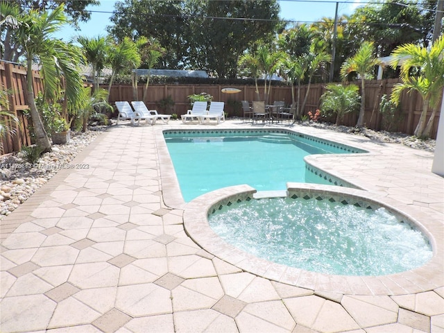 view of swimming pool featuring an in ground hot tub and a patio