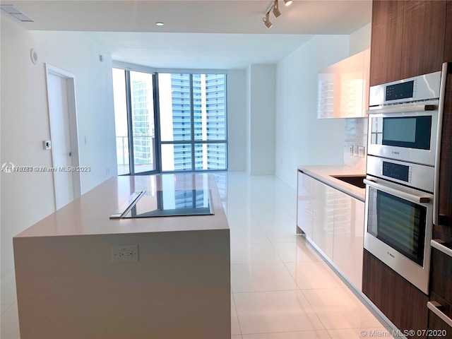 kitchen featuring light tile floors, rail lighting, and double oven