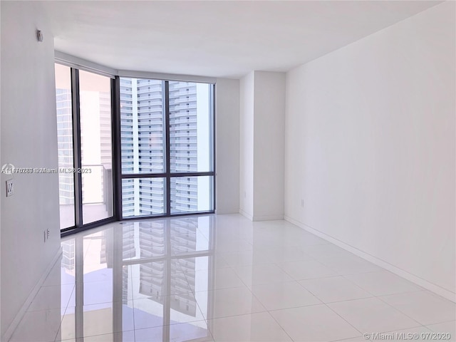 empty room featuring a healthy amount of sunlight, floor to ceiling windows, and light tile floors