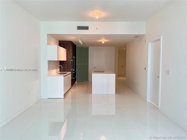 spare room featuring light tile flooring and a wall of windows