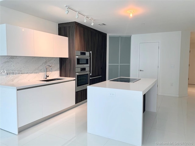 kitchen featuring a center island, light tile flooring, black electric cooktop, sink, and track lighting