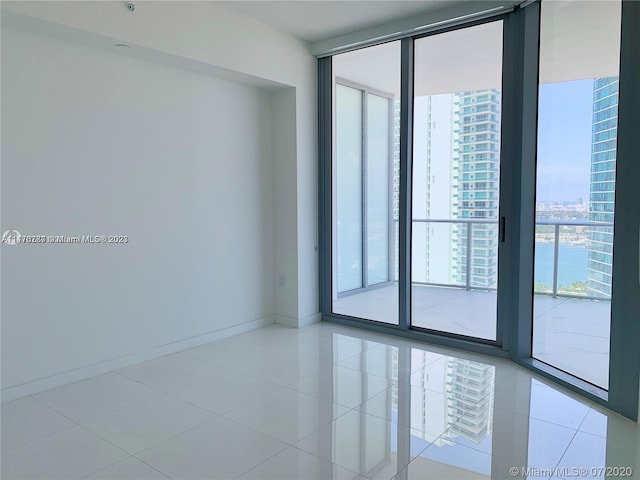 tiled empty room featuring a wall of windows