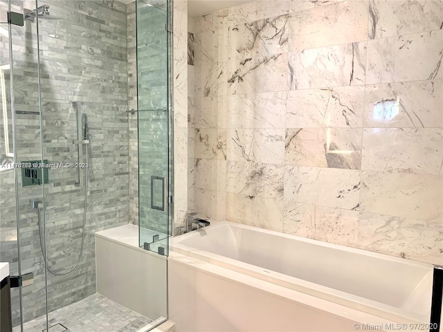 bathroom featuring tile walls and independent shower and bath