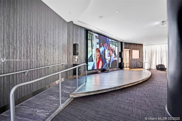 interior space featuring wooden walls and dark carpet