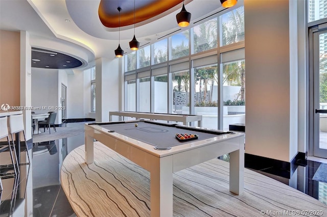 game room with plenty of natural light, billiards, a tray ceiling, and a high ceiling