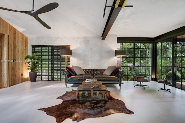 living room featuring vaulted ceiling with beams, wood walls, concrete flooring, and ceiling fan