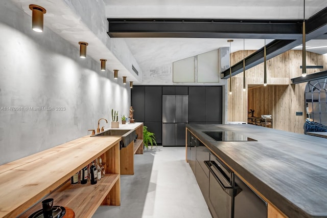 kitchen with stainless steel built in fridge, wood counters, hanging light fixtures, and sink