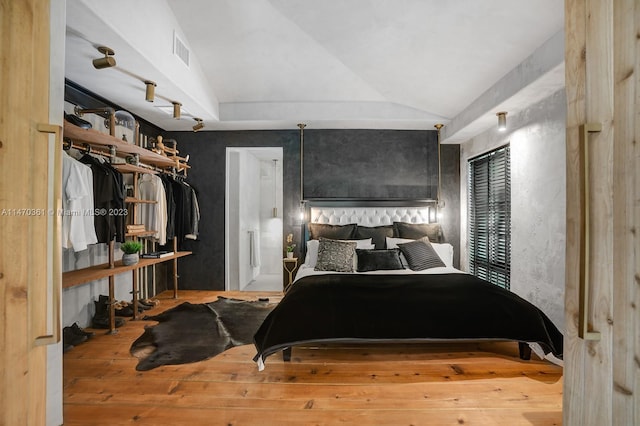 bedroom featuring light hardwood / wood-style floors, a closet, track lighting, and lofted ceiling