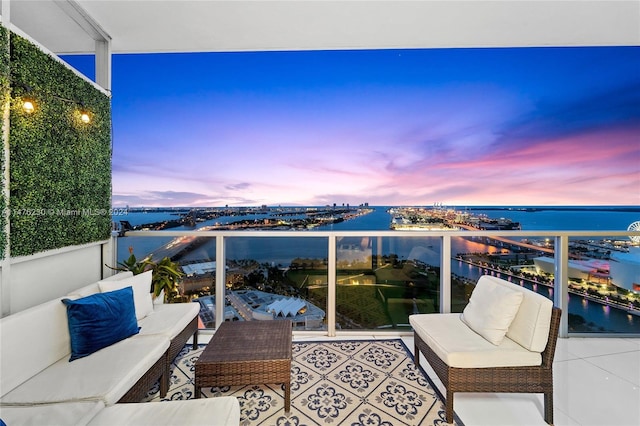 balcony at dusk featuring a water view and an outdoor hangout area