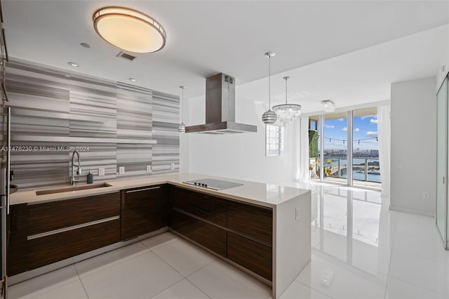 kitchen featuring pendant lighting, light tile floors, sink, a chandelier, and wall chimney range hood