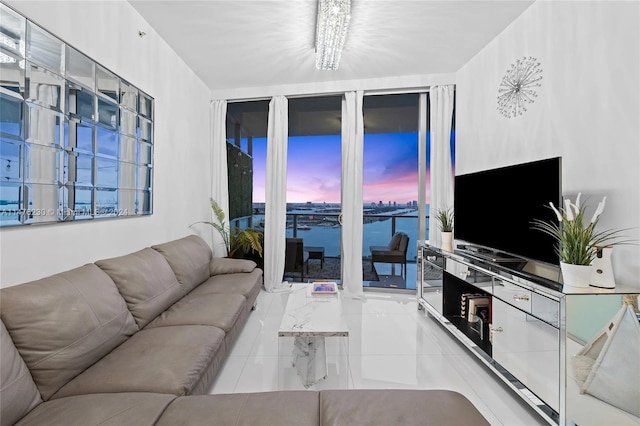 living room with light tile floors, an inviting chandelier, and a water view