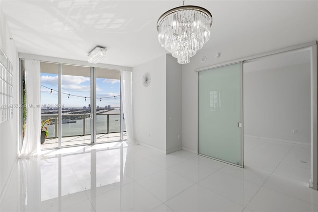 unfurnished room with an inviting chandelier, expansive windows, and light tile floors