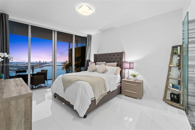 tiled bedroom with access to outside, expansive windows, and a water view