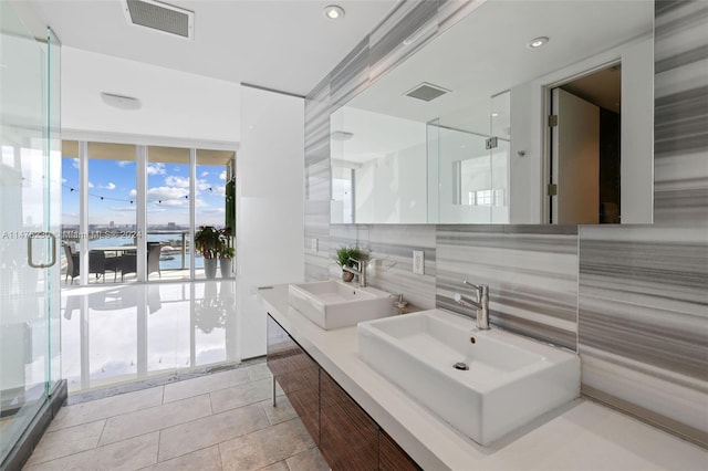 bathroom with a water view, tile floors, dual sinks, oversized vanity, and tasteful backsplash