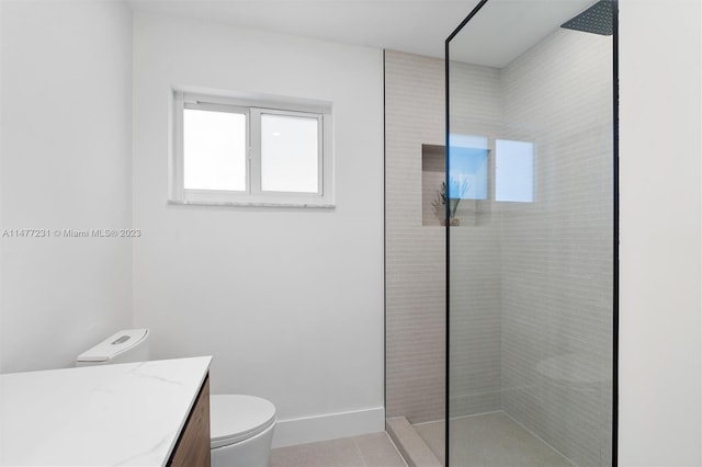 bathroom featuring tile patterned floors, a tile shower, vanity, and toilet